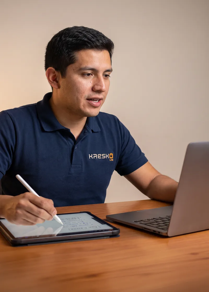 Docente de KRESKO LAB dando una clase en línea, con su tableta y su laptop